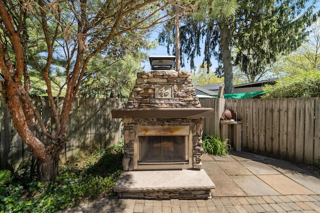 view of patio featuring an outdoor stone fireplace and a fenced backyard