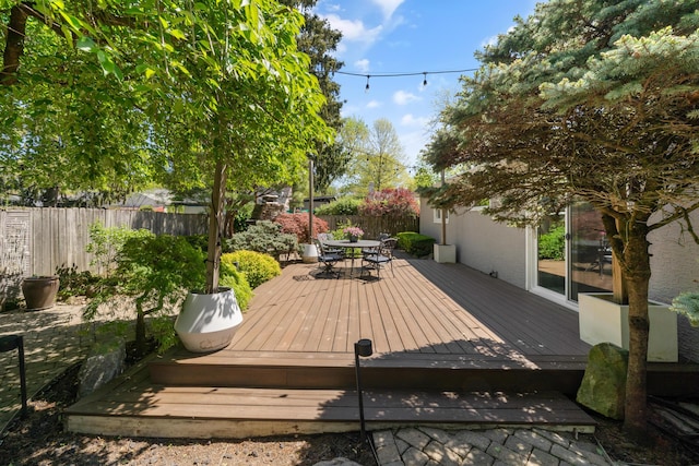 wooden terrace with outdoor dining area and fence
