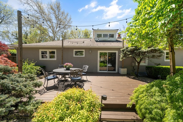 back of house with a wooden deck, outdoor dining space, and stucco siding