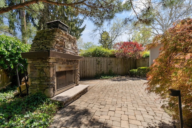 view of patio / terrace with fence and an outdoor stone fireplace