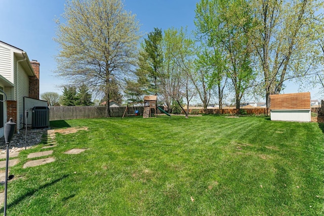 view of yard featuring an outdoor structure, cooling unit, a playground, a storage shed, and a fenced backyard