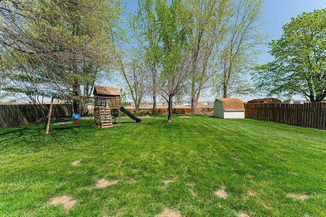 view of yard with a fenced backyard, a playground, and a storage shed