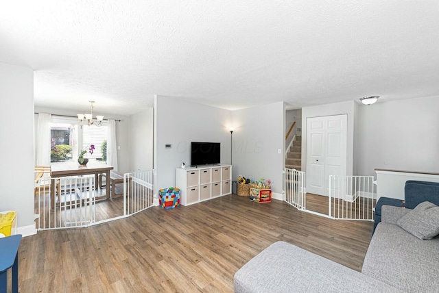 living area with an inviting chandelier, a textured ceiling, wood finished floors, and baseboards