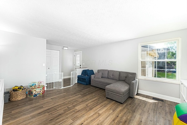 living area with baseboards, visible vents, wood finished floors, and a textured ceiling