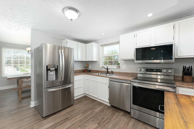kitchen with white cabinetry, wood finished floors, appliances with stainless steel finishes, and a sink