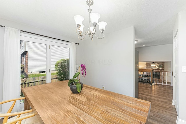 dining space featuring a textured ceiling, wood finished floors, and a notable chandelier
