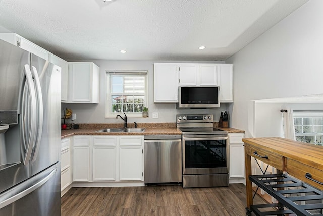 kitchen with a sink, white cabinetry, stainless steel appliances, and dark wood finished floors