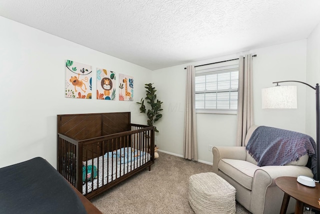 carpeted bedroom featuring baseboards, a crib, and a textured ceiling