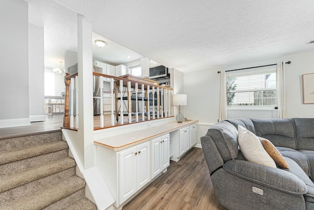 living area featuring stairway, wood finished floors, a textured ceiling, and baseboards