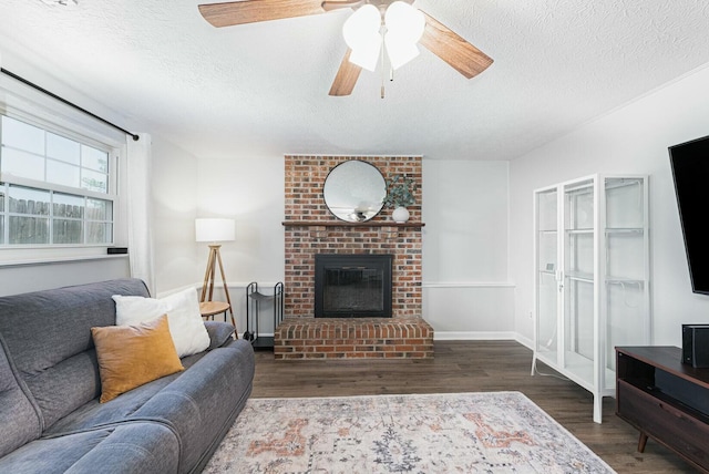 living room with wood finished floors, a ceiling fan, a textured ceiling, and a fireplace