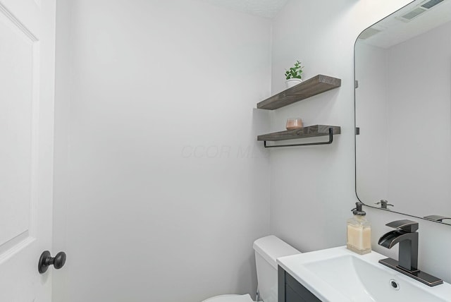bathroom with toilet, visible vents, and vanity