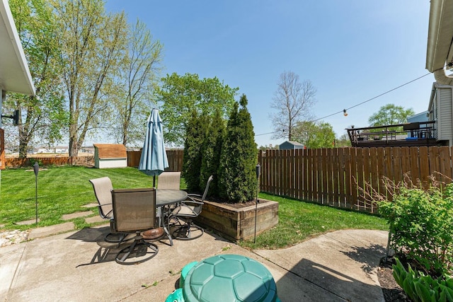 view of patio / terrace with an outbuilding, a storage shed, outdoor dining area, and a fenced backyard