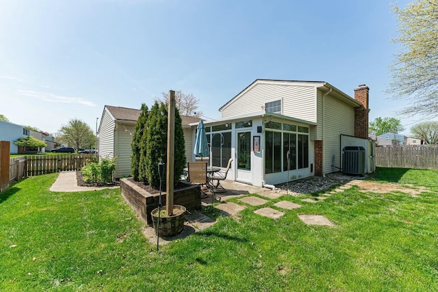 rear view of house with a chimney, a fenced backyard, a patio, and a sunroom
