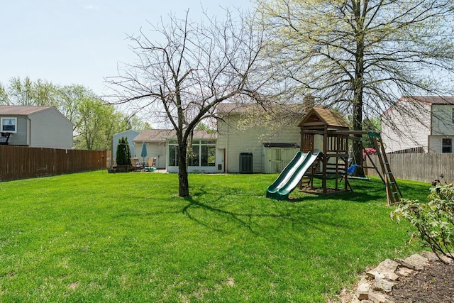 view of yard featuring a fenced backyard, a playground, and central air condition unit