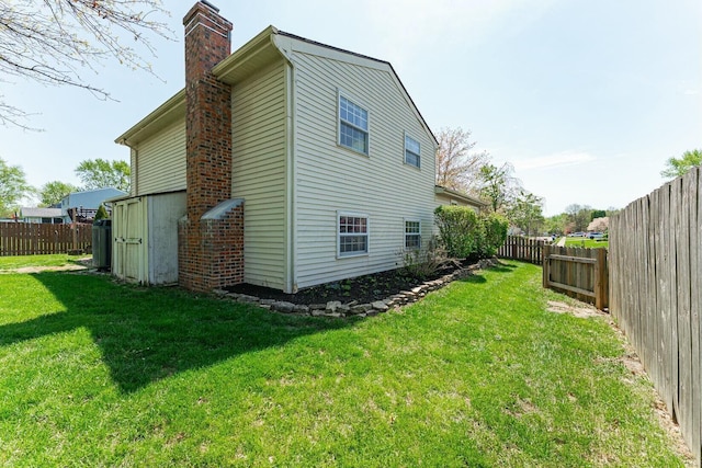 back of property with a chimney, a yard, and a fenced backyard