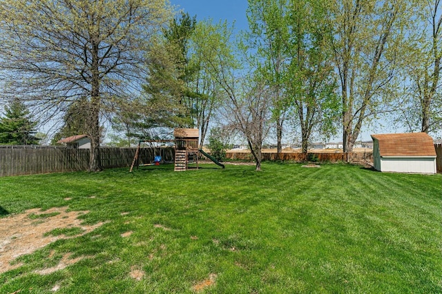view of yard with a fenced backyard, a shed, an outbuilding, and a playground