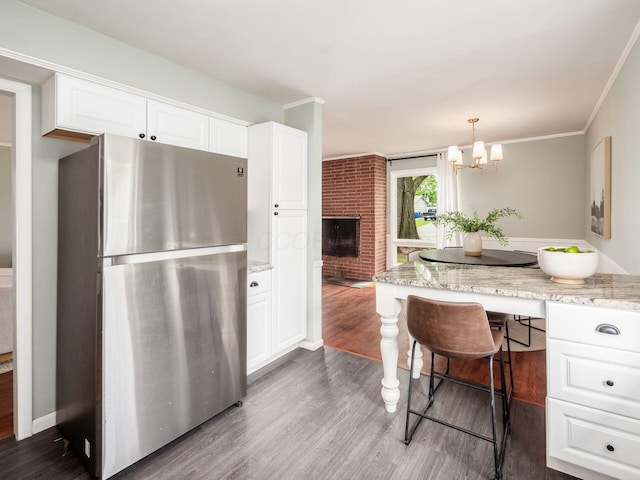 kitchen featuring white cabinetry, dark wood-style flooring, a kitchen bar, and freestanding refrigerator