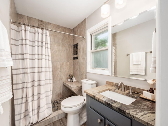 full bath with wood finished floors, toilet, vanity, and tiled shower