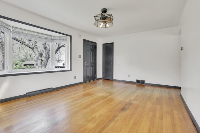 unfurnished room with wood-type flooring, baseboards, visible vents, and an inviting chandelier