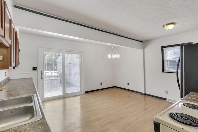 kitchen with freestanding refrigerator, white electric range, a sink, light wood finished floors, and a notable chandelier