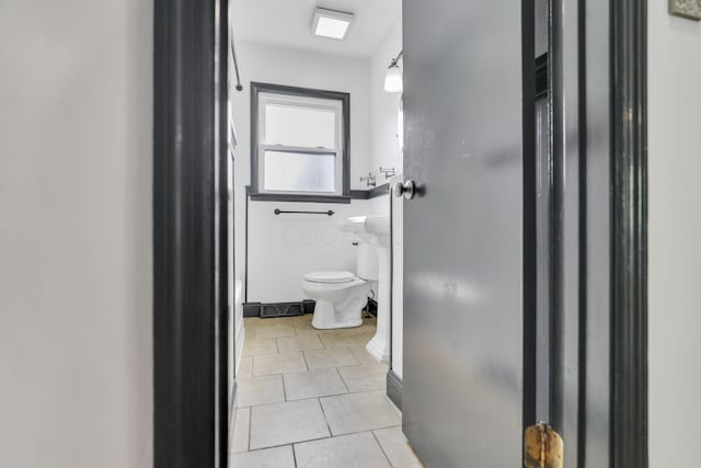 bathroom with baseboards, tile patterned flooring, and toilet
