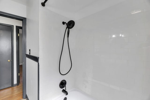 details with shower / bathtub combination and wood finished floors