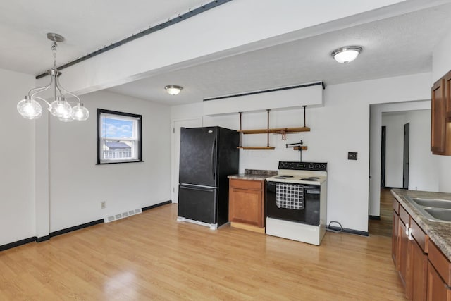kitchen featuring freestanding refrigerator, white range with electric cooktop, visible vents, and brown cabinetry