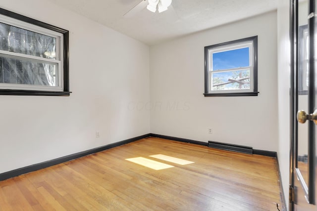 spare room with baseboards, a ceiling fan, wood finished floors, and visible vents