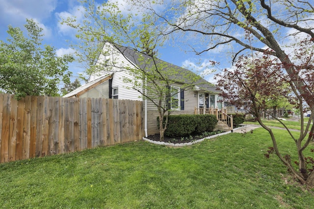 view of side of home with fence and a yard