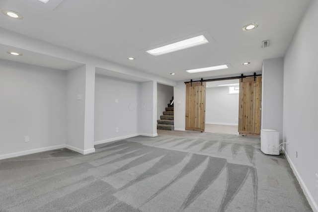 below grade area featuring light carpet, recessed lighting, and a barn door