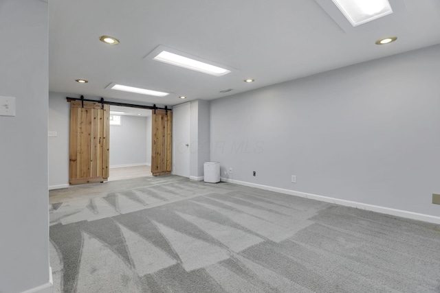 basement with recessed lighting, baseboards, light colored carpet, and a barn door