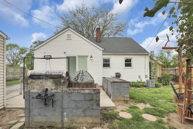 back of property with a fenced backyard, a lawn, a chimney, and cooling unit