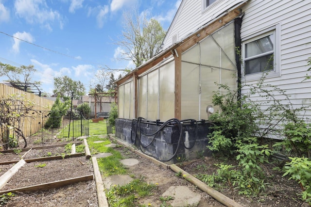 view of side of home featuring fence and a vegetable garden