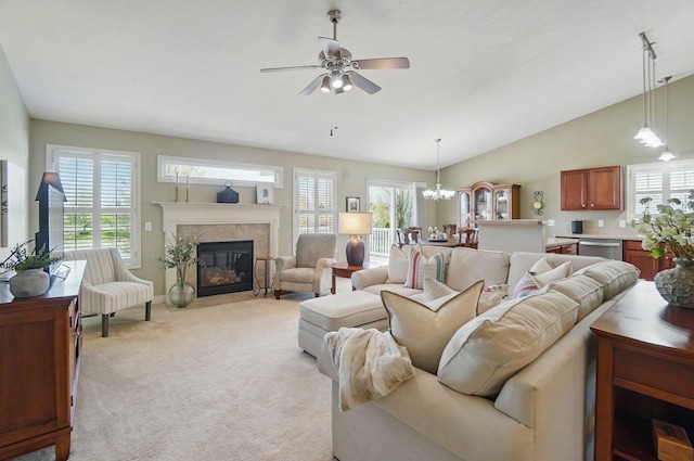 living area with ceiling fan with notable chandelier, lofted ceiling, a premium fireplace, and light carpet
