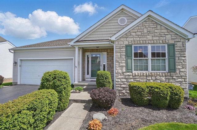 ranch-style home featuring an attached garage, aphalt driveway, and stone siding