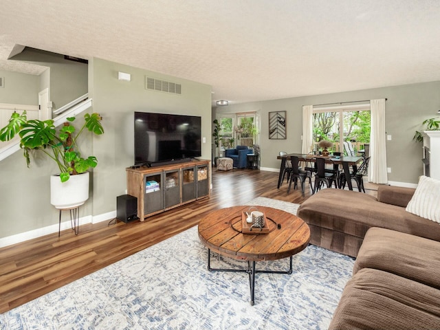 living area with wood finished floors, visible vents, a healthy amount of sunlight, and baseboards