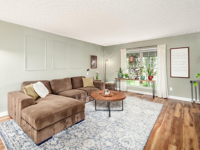 living room featuring baseboards, visible vents, wood finished floors, and a textured ceiling