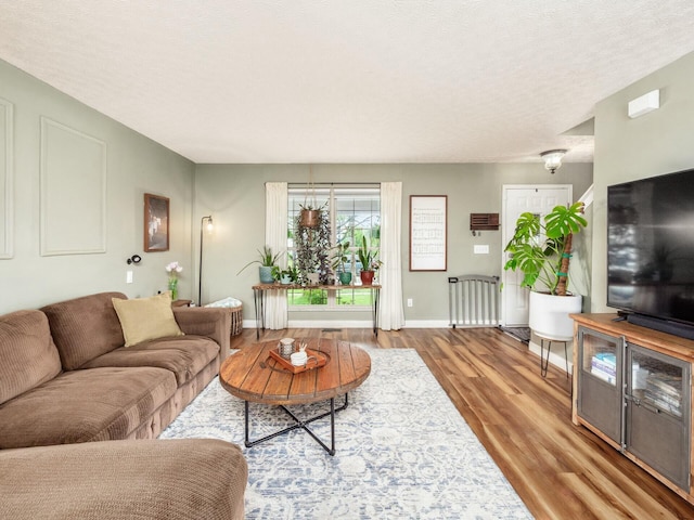 living area featuring a textured ceiling, wood finished floors, and baseboards