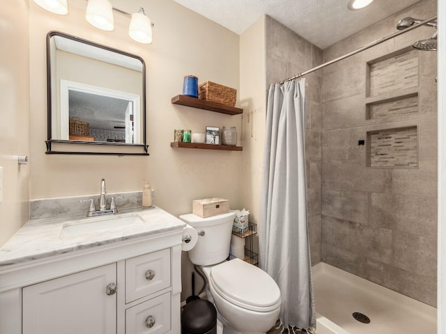 bathroom with a shower stall, toilet, a textured ceiling, and vanity