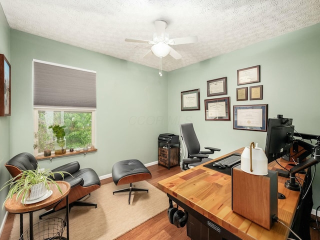 office area with a textured ceiling, wood finished floors, a ceiling fan, and baseboards