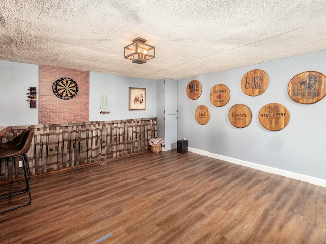 unfurnished room featuring a textured ceiling, wood finished floors, and baseboards