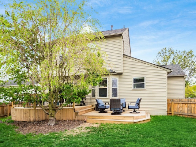 rear view of house featuring roof with shingles, a yard, a wooden deck, and a fenced backyard