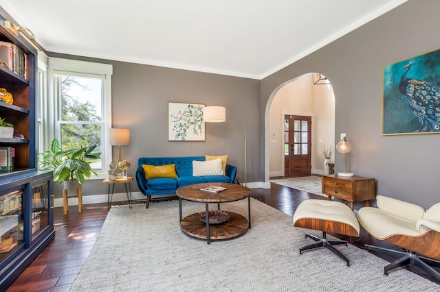 living area featuring baseboards, arched walkways, and hardwood / wood-style flooring