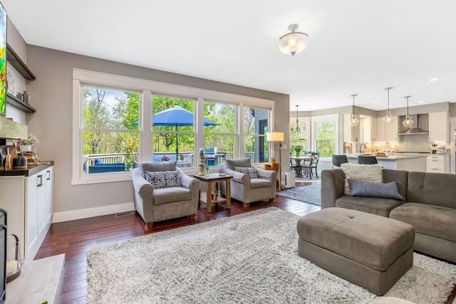 living room featuring baseboards, recessed lighting, dark wood-style flooring, and a healthy amount of sunlight