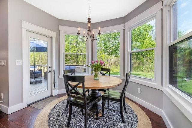 dining area featuring baseboards, dark wood-style flooring, a healthy amount of sunlight, and an inviting chandelier