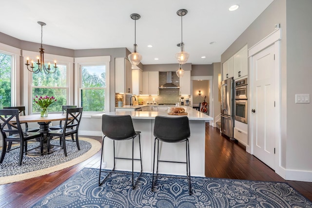 kitchen with light countertops, plenty of natural light, stainless steel appliances, and wall chimney exhaust hood