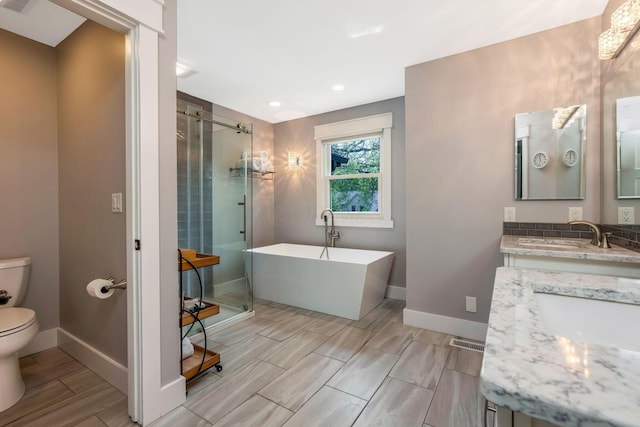 bathroom with vanity, toilet, recessed lighting, a soaking tub, and a stall shower