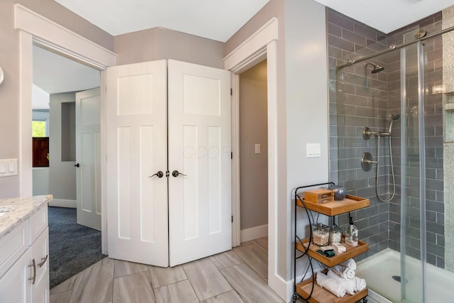 full bathroom featuring vanity, baseboards, and a shower stall