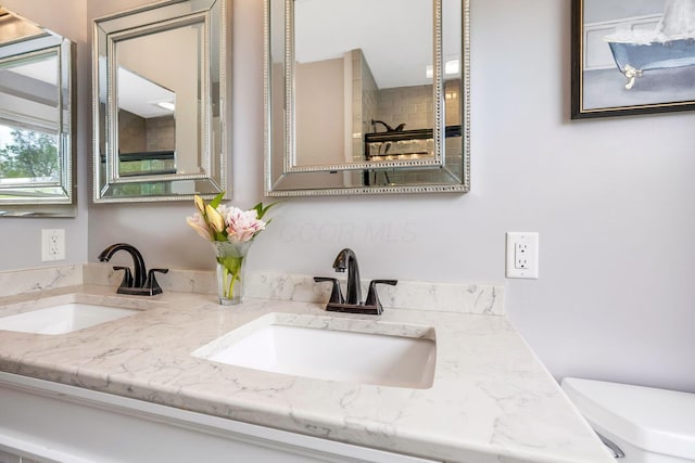 bathroom featuring a sink, toilet, and double vanity