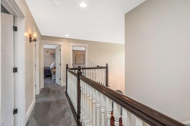 hall with recessed lighting, baseboards, an upstairs landing, and dark carpet